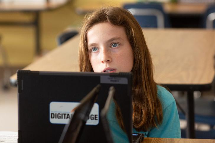 A sixth-grade girl works on a project alone in history class